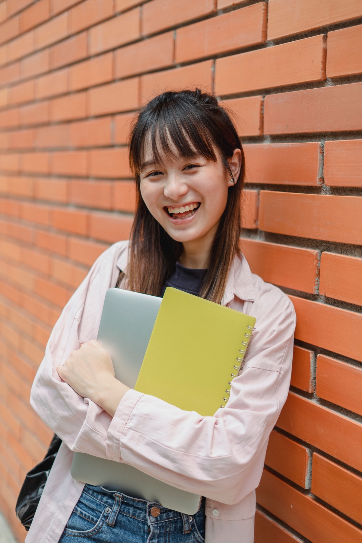 手持电脑与笔记本、面带微笑的年轻大学生